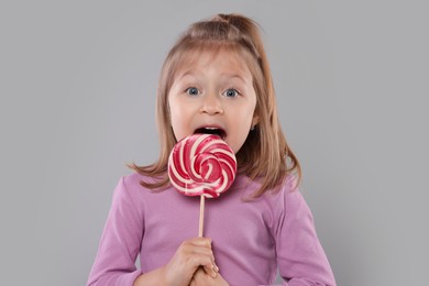 Portrait of cute girl with lollipop on light grey background