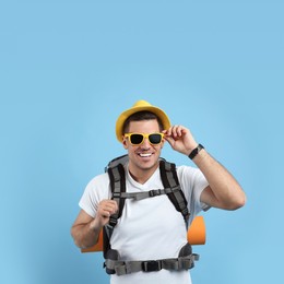 Male tourist with travel backpack on turquoise background, space for text