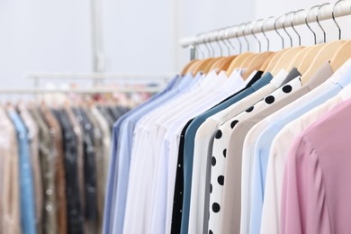 Photo of Dry-cleaning service. Many different clothes hanging on rack indoors, closeup