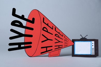 Image of Big paper megaphone with words Hype and TV on light grey background