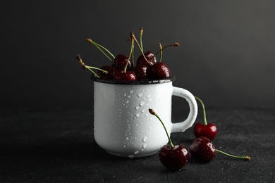 Mug with sweet red cherries on table