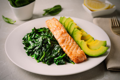 Image of Tasty salmon with spinach and avocado on light table, closeup. Food photography  