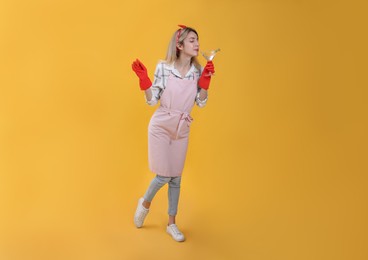 Photo of Young housewife with glass of martini on yellow background