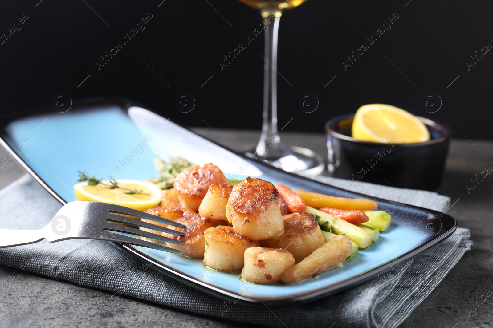 Photo of Delicious fried scallops with asparagus served on grey table