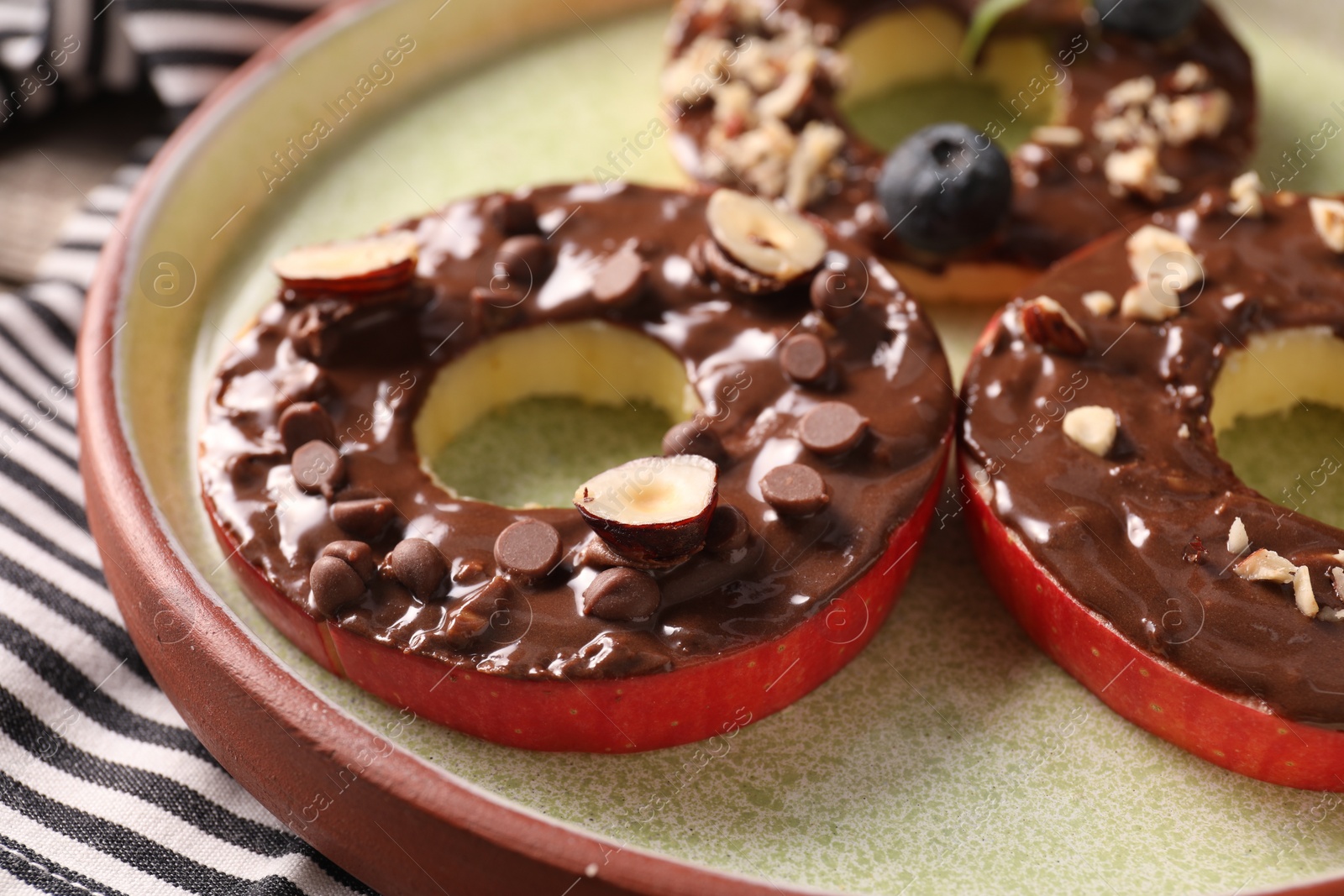 Photo of Fresh apples with nut butter, hazelnuts and chocolate chips on table, closeup