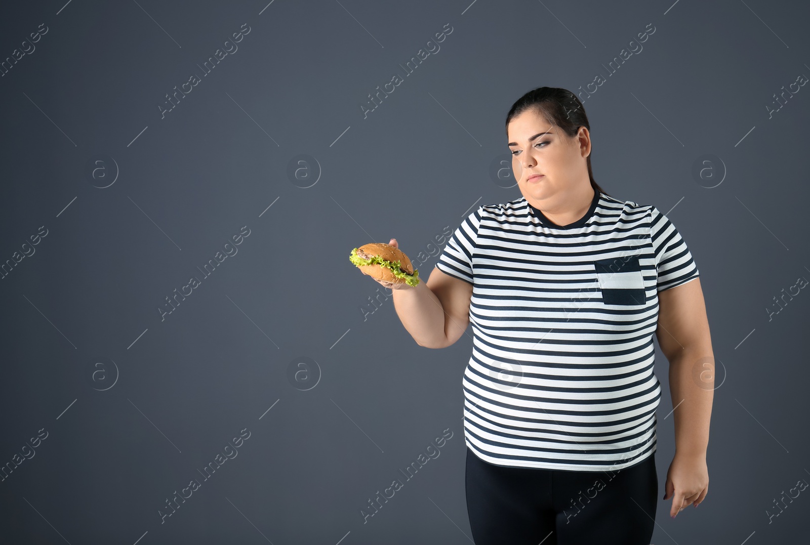 Photo of Overweight woman with hamburger and space for text on gray background