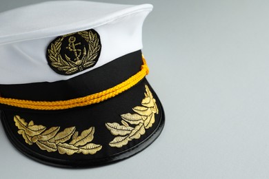 Photo of Peaked cap with accessories on light grey background, closeup. Space for text