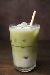Glass of tasty iced matcha latte on wooden table