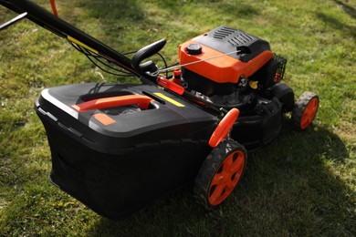 Modern lawn mower on green grass outdoors