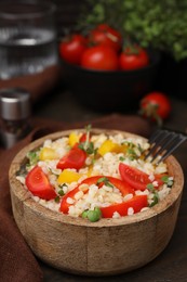 Cooked bulgur with vegetables in bowl on wooden table
