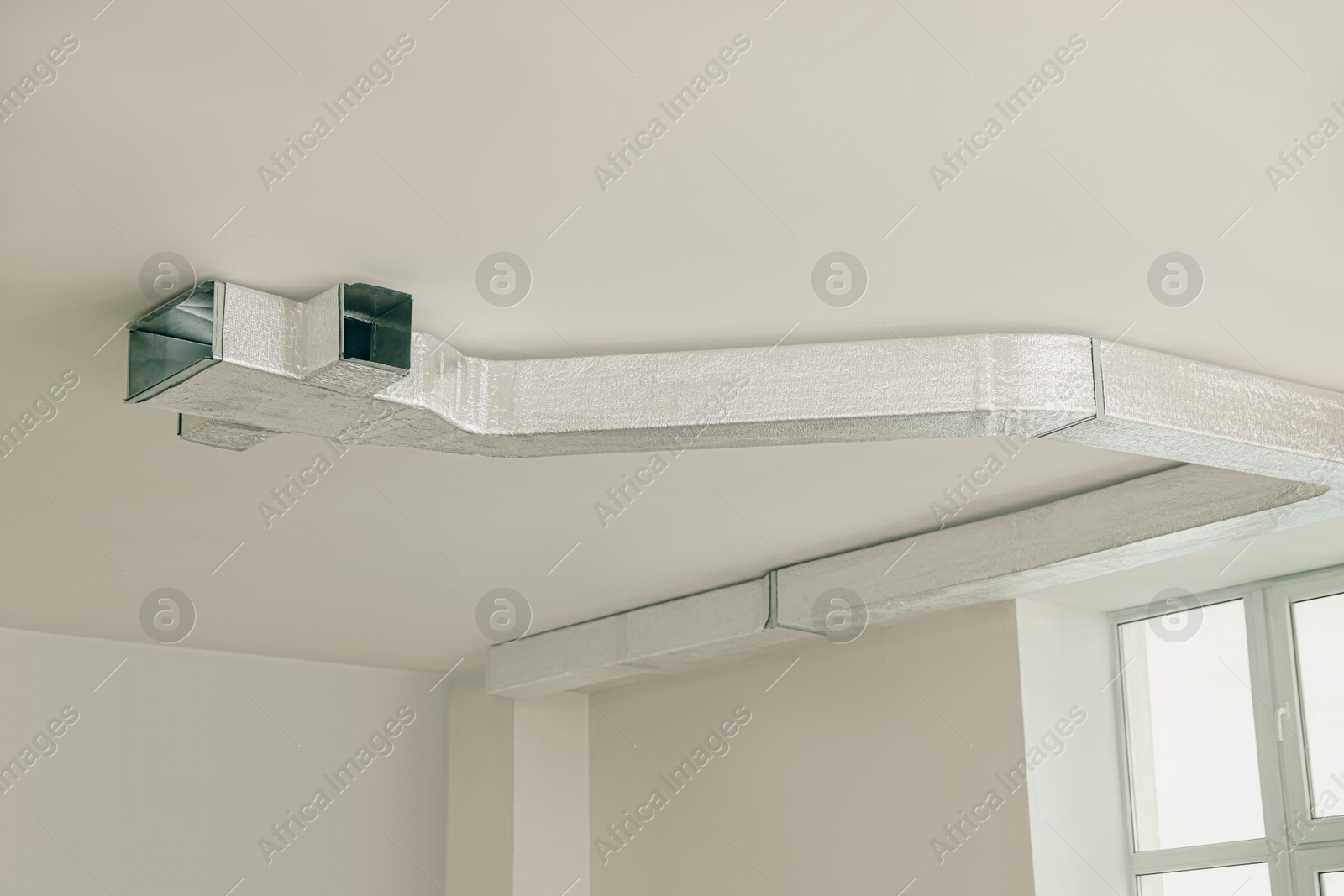 Photo of Modern pipe installed on ceiling indoors. Home renovation