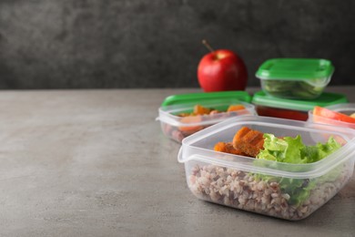 Set of plastic containers with fresh food on light grey table, space for text