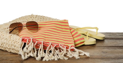 Beach bag with towel, flip flops and sunglasses on wooden surface against white background
