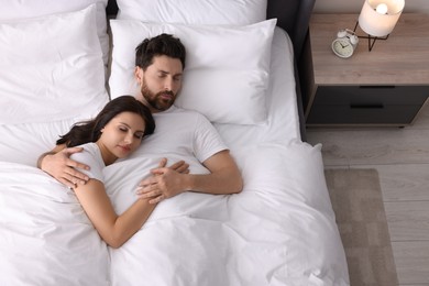 Lovely couple sleeping together in bed at home, top view