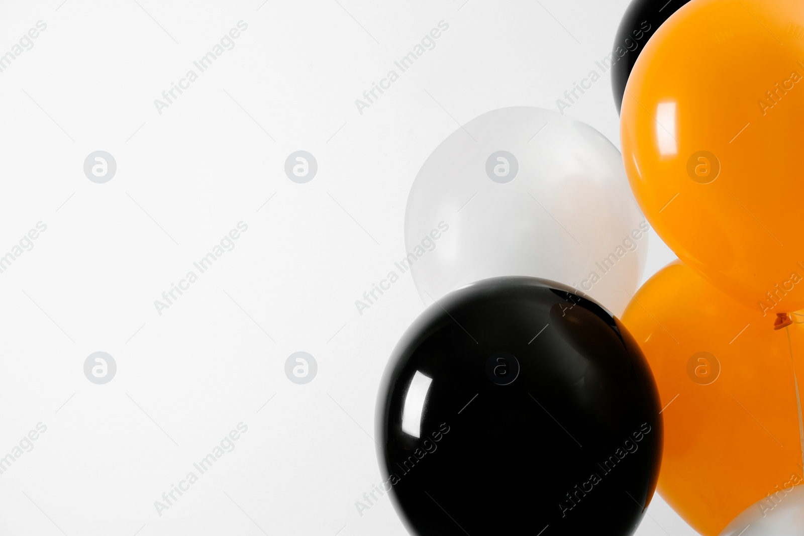 Photo of Colorful balloons on light background, space for text. Halloween party