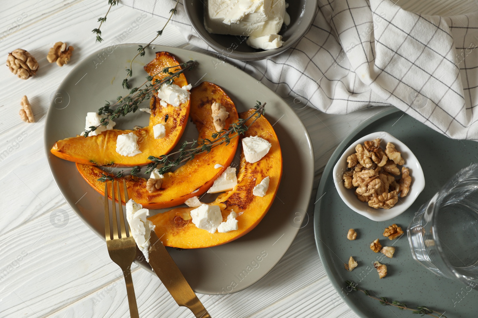 Photo of Delicious pumpkin slices served with thyme and cheese on white wooden table, flat lay