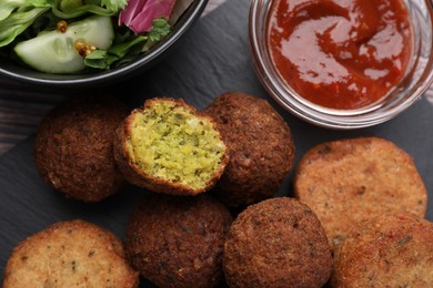 Delicious vegan cutlets, falafel balls and sauce on slate board, flat lay