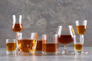 Many different liqueurs in glasses on grey textured table