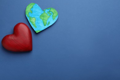 Photo of Model of planet and red heart on blue background, flat lay with space for text. Earth Day
