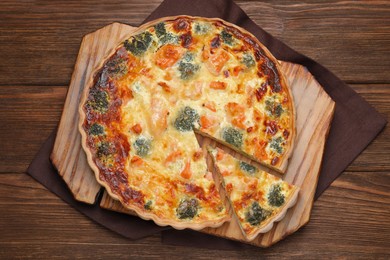 Delicious homemade quiche with salmon and broccoli on wooden table, top view