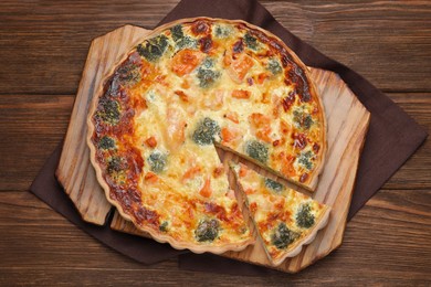 Photo of Delicious homemade quiche with salmon and broccoli on wooden table, top view