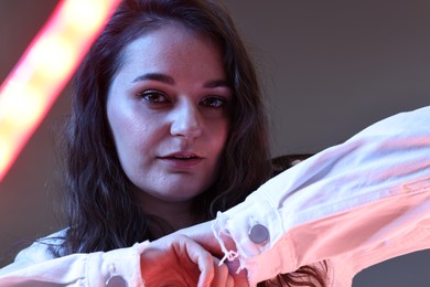 Portrait of beautiful young woman on color background with neon lights