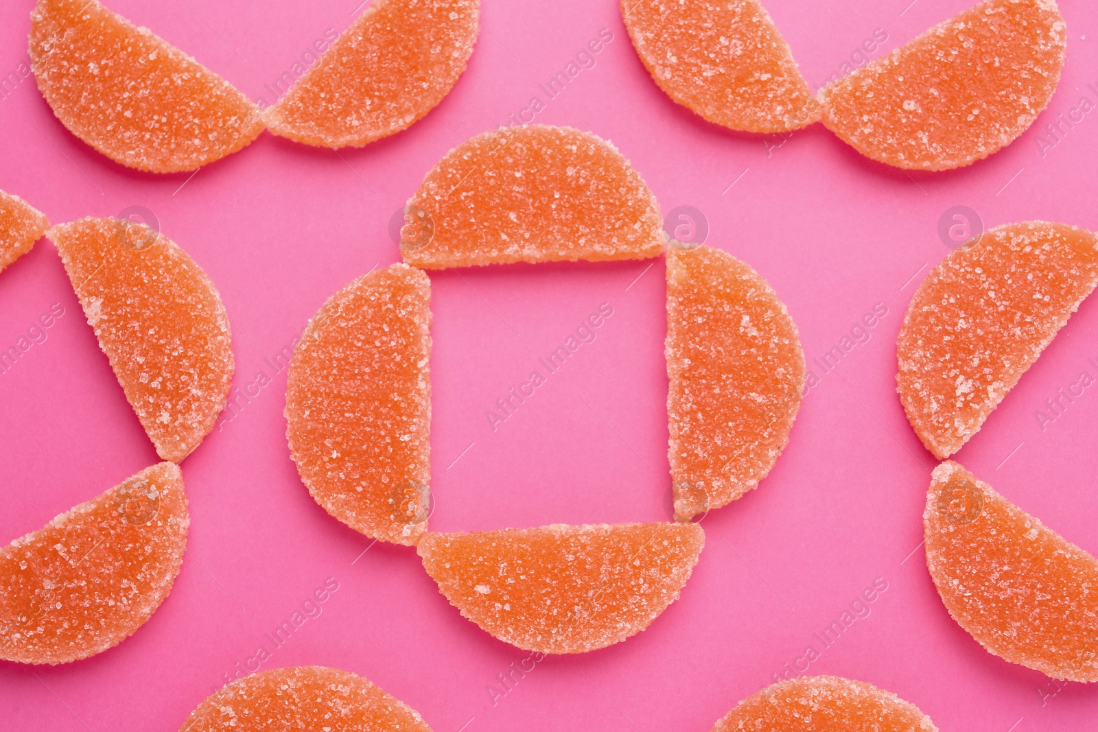 Photo of Delicious orange marmalade candies on pink background, flat lay