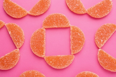 Delicious orange marmalade candies on pink background, flat lay