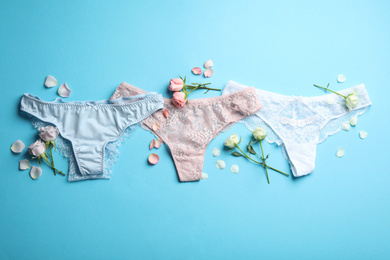Set of elegant women's underwear and flowers on light blue background, flat lay