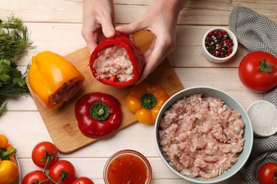 Photo of Woman making stuffed peppers with ground meat at white wooden table, top view