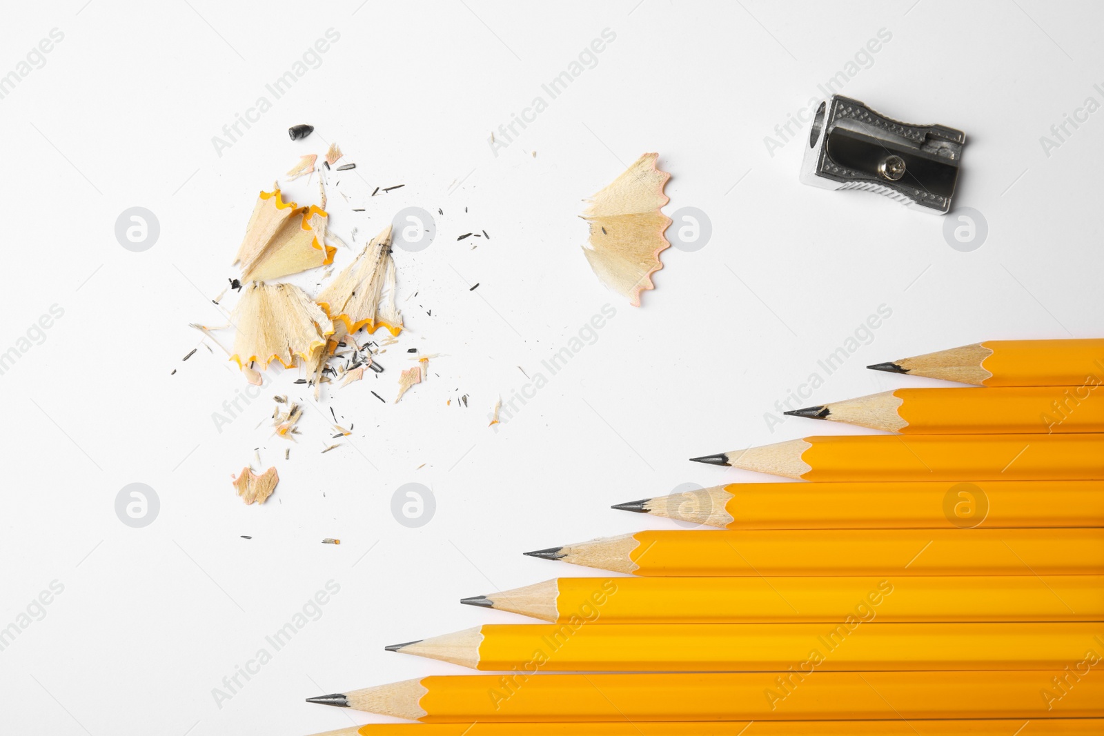 Photo of Graphite pencils, shavings and sharpener on white background, top view
