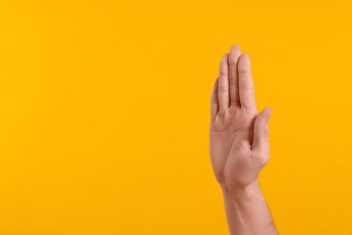 Photo of Man giving high five on yellow background, closeup of hand. Space for text