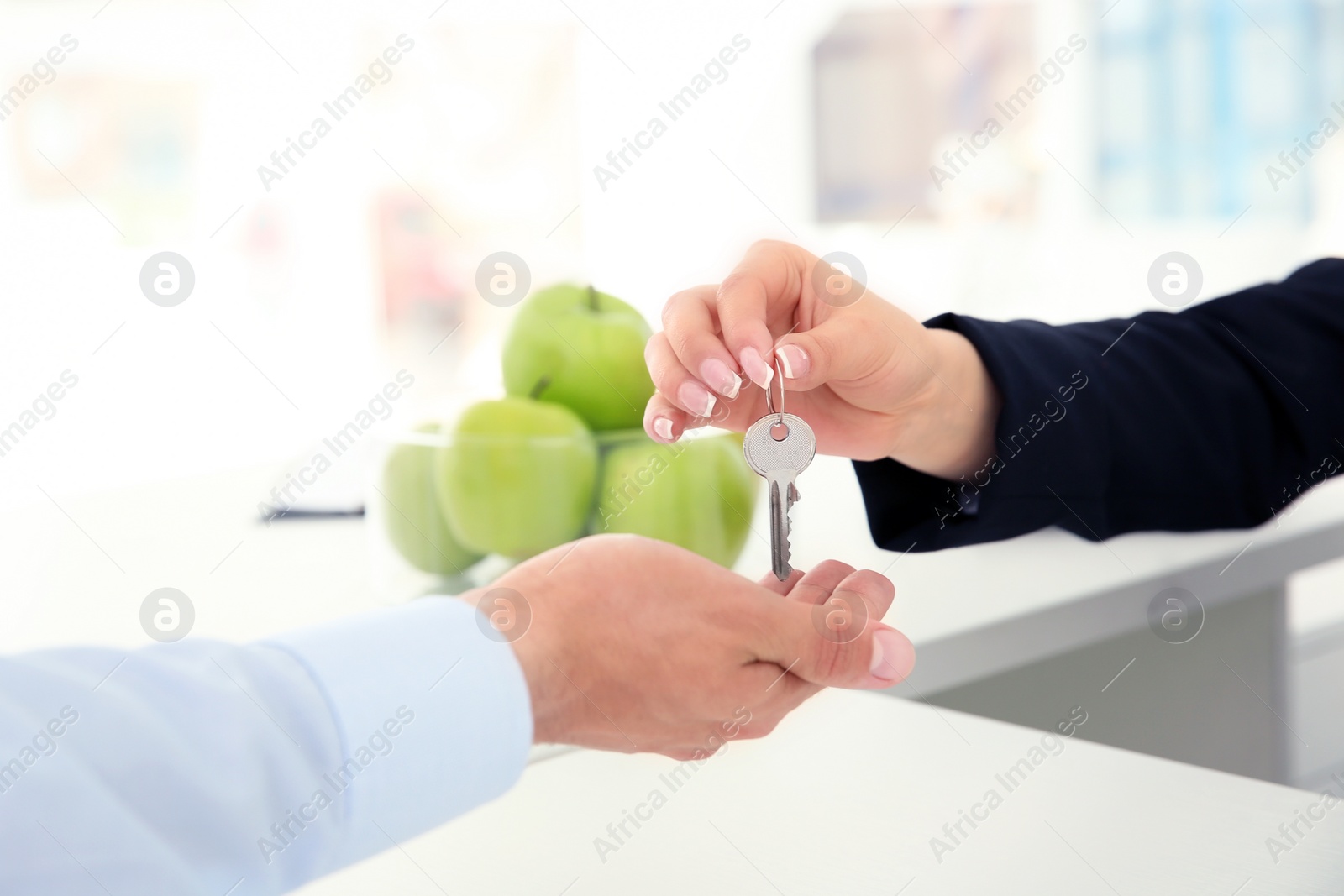 Photo of Young man receiving key from receptionist in hotel, closeup