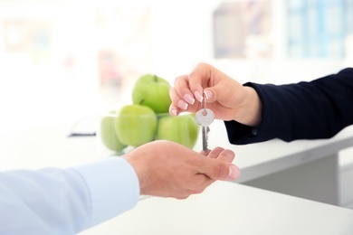 Young man receiving key from receptionist in hotel, closeup