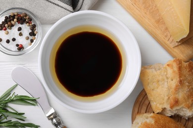 Photo of Bowl of balsamic vinegar with oil, bread and spices on white table, flat lay
