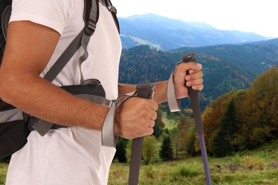 Man with backpack and trekking poles on sunny day, closeup