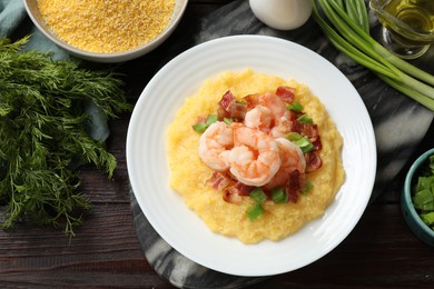 Photo of Plate with fresh tasty shrimps, bacon, grits and green onion on dark wooden table, flat lay