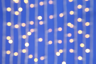 Blurred view of glowing Christmas lights on color background, top view