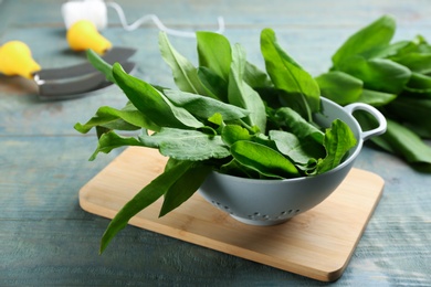 Photo of Fresh green sorrel leaves in colander on light blue wooden table, closeup