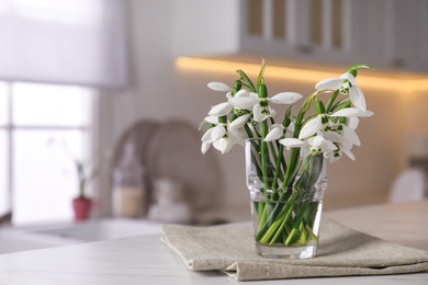 Photo of Beautiful snowdrops in vase on light table. Space for text