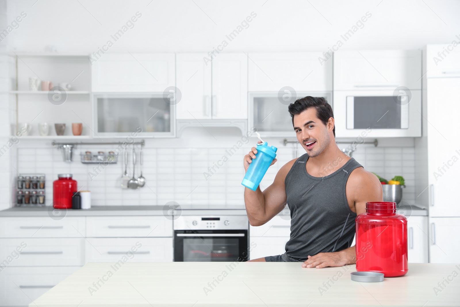 Photo of Young athletic man with protein shake powder in kitchen, space for text