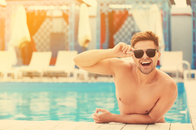 Image of Handsome young man in swimming pool on sunny day