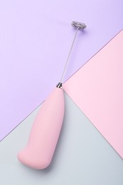 Pink milk frother wand on color background, top view