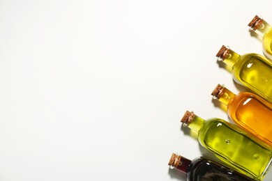 Vegetable fats. Different cooking oils in glass bottles on white background, flat lay. Space for text