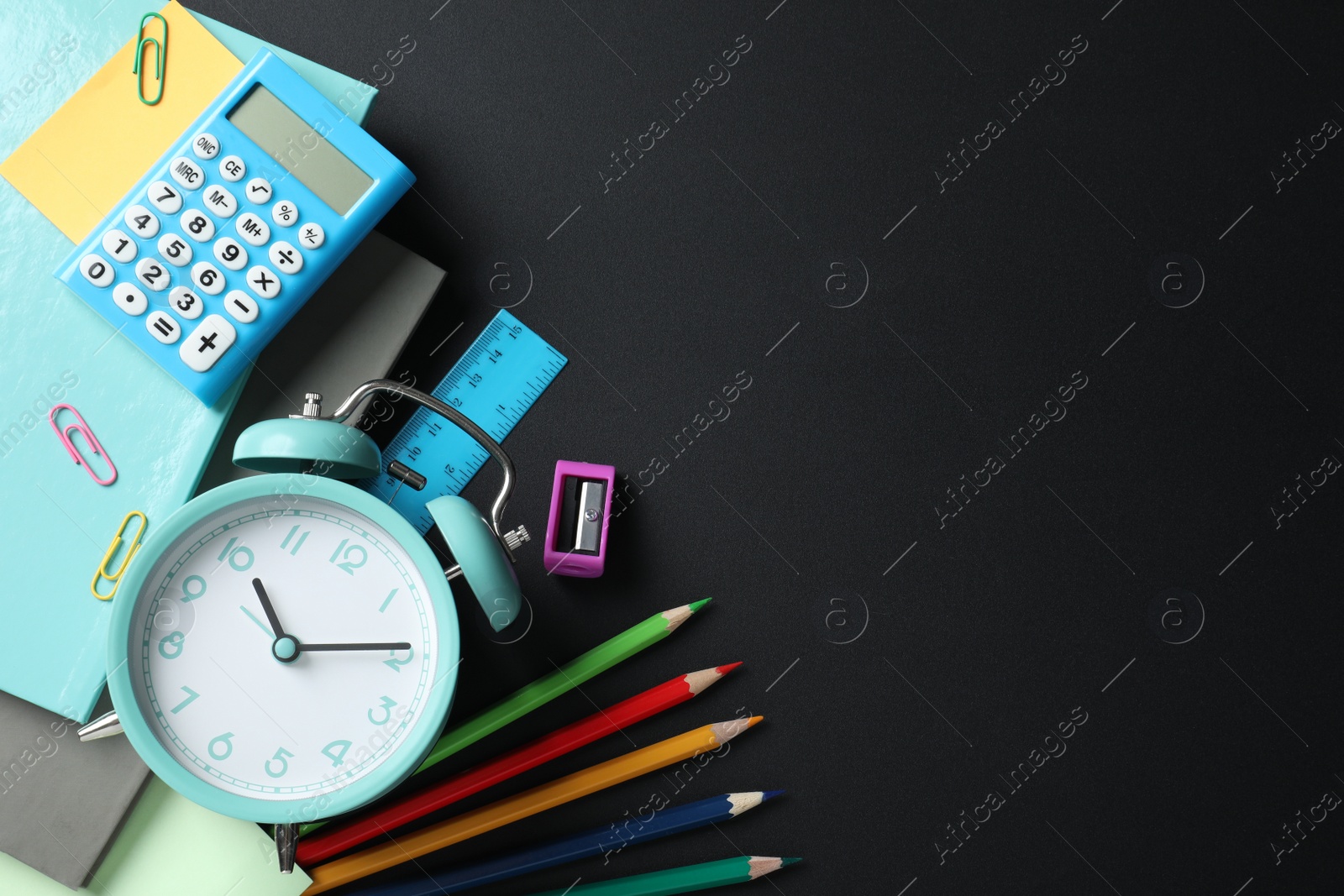 Photo of Flat lay composition with alarm clock and different stationery on black background, space for text. School time