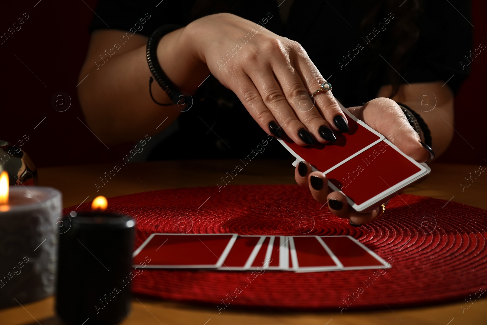 Photo of Soothsayer predicting future with cards at table indoors, closeup