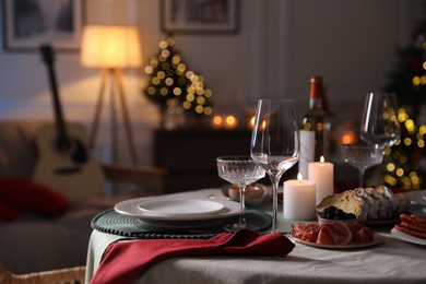 Photo of Christmas table setting with burning candles, appetizers and dishware. Space for text