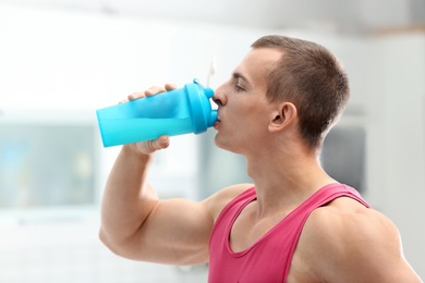 Photo of Athletic young man drinking protein shake in kitchen