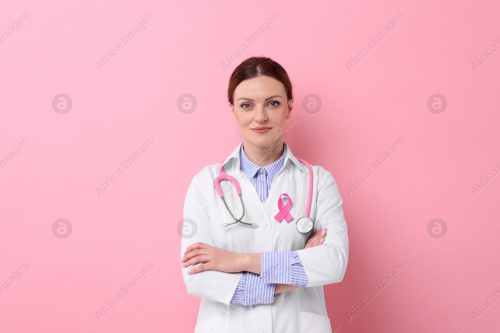 Photo of Mammologist with pink ribbon on color background. Breast cancer awareness