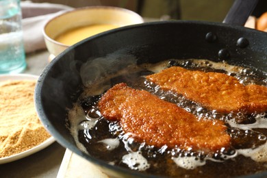 Photo of Cooking schnitzels in frying pan, closeup view